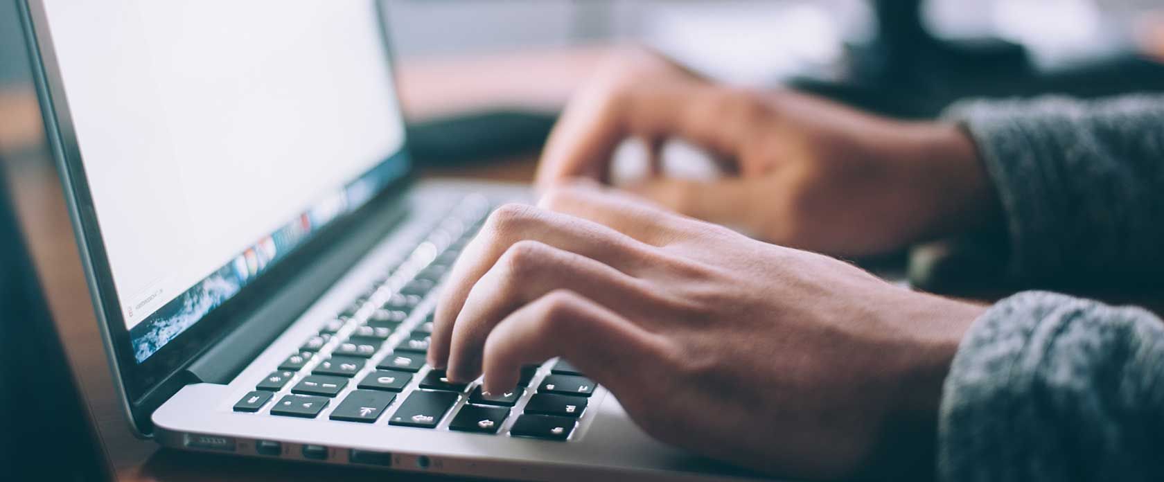 Hände in Nahaufnahme, die eine Computertastatur bedienen.