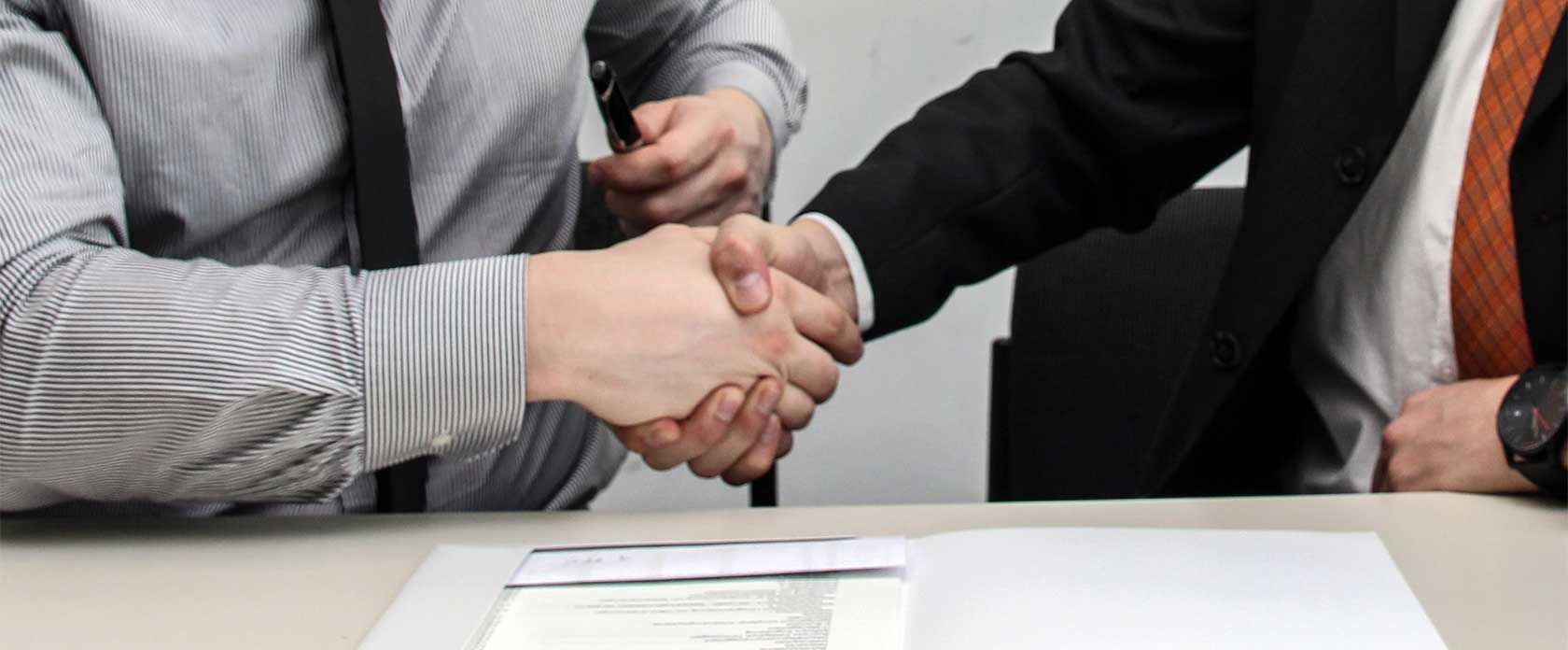 Zwei Männer in Business-Kleidung schütteln sich die Hand.