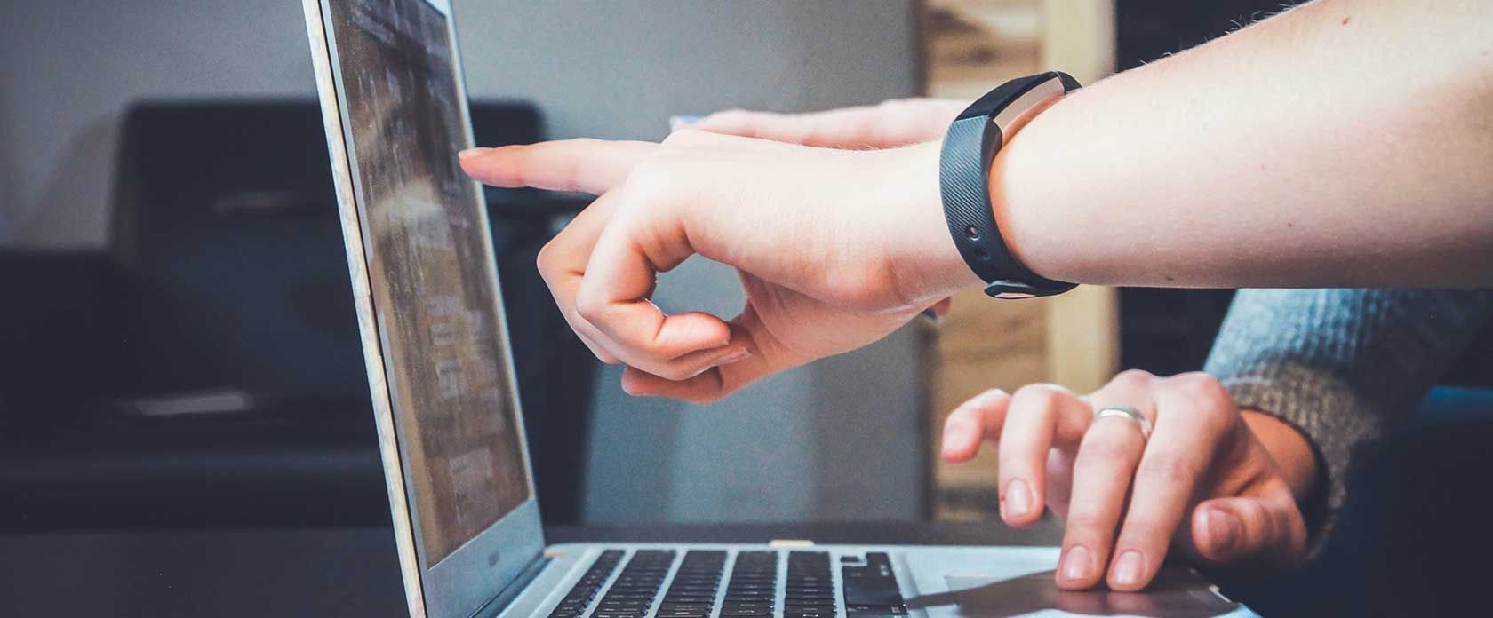 Der Finger einer Hand zeigt auf etwas an einem Bildschirm.