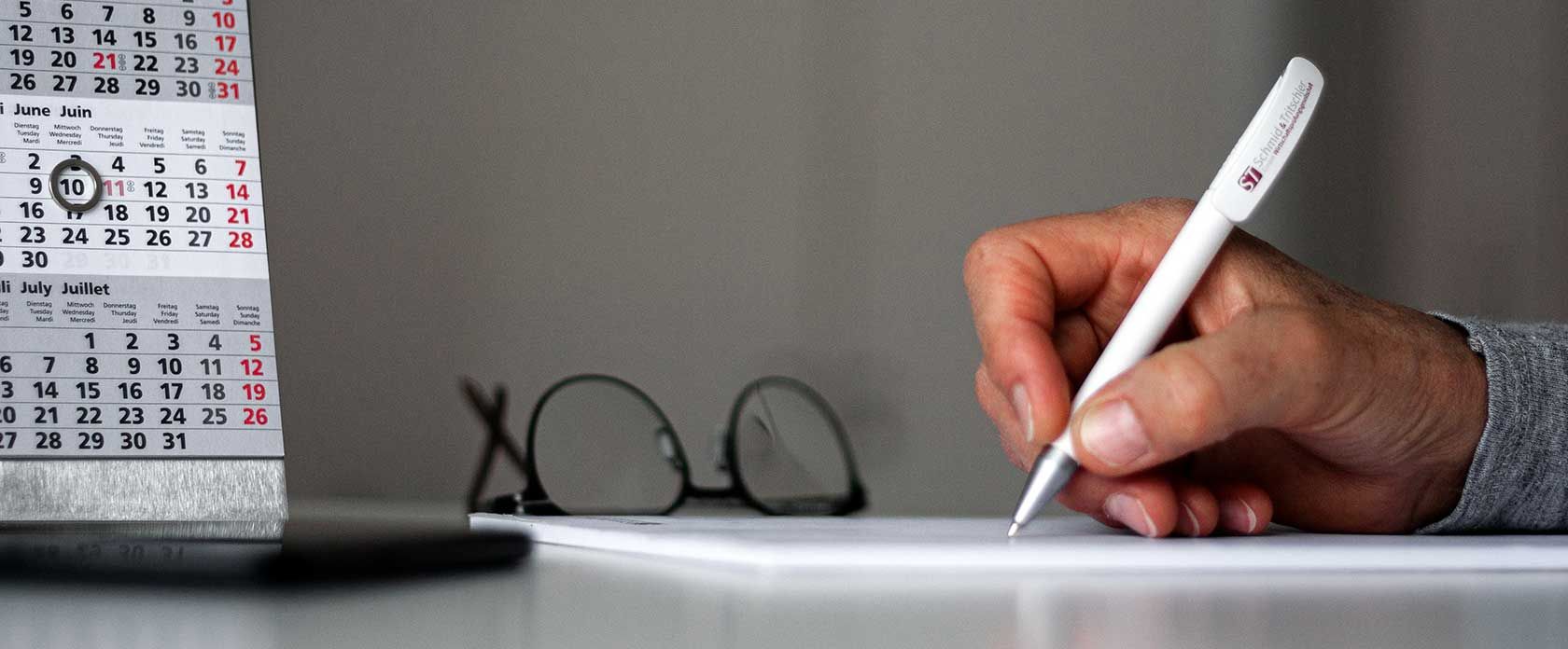 Eine Hand in Nahaufnahme, die Notizen mit einem Kugelschreiber auf einem Block macht.